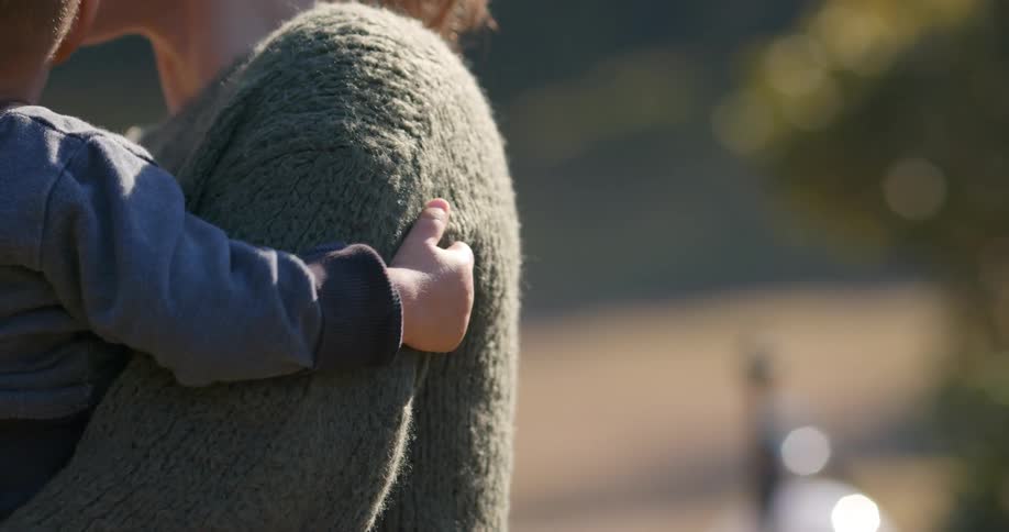 A woman holds and talks to her infant son as they stand outside