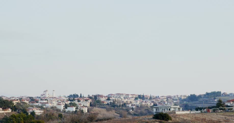 Village of all white buildings with tan rooftops on hills
