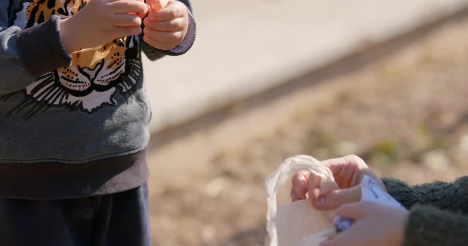 A woman gives a young boy a piece of candy