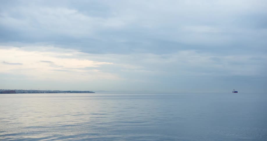 Gentle ripples on the ocean off the coast of a city on a cloudy day
