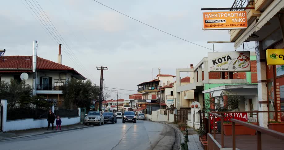 Pedestrians and light traffic travel along a street in a small city during the day