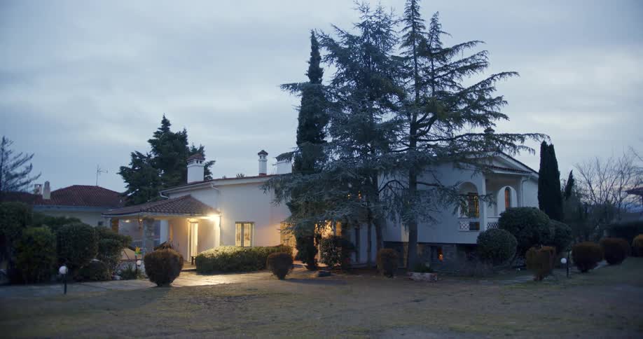 Outdoor lights shine on landscaping near building under overcast sky
