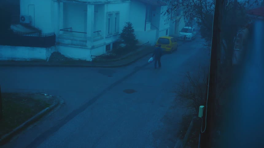 A person holding a bag walking on a street with vehicles