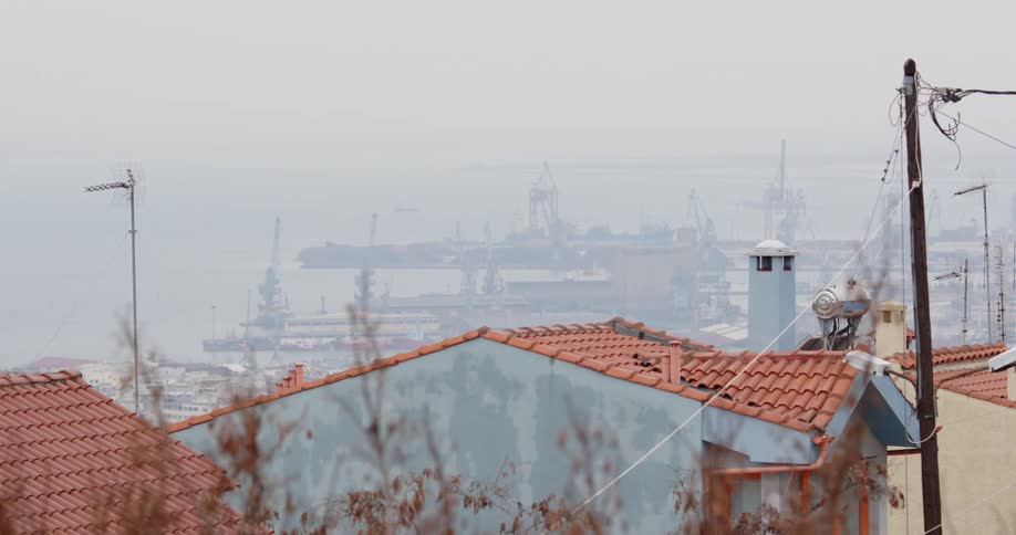 Red tiled roof of houses in a small town near a pier on an overcast misty day
