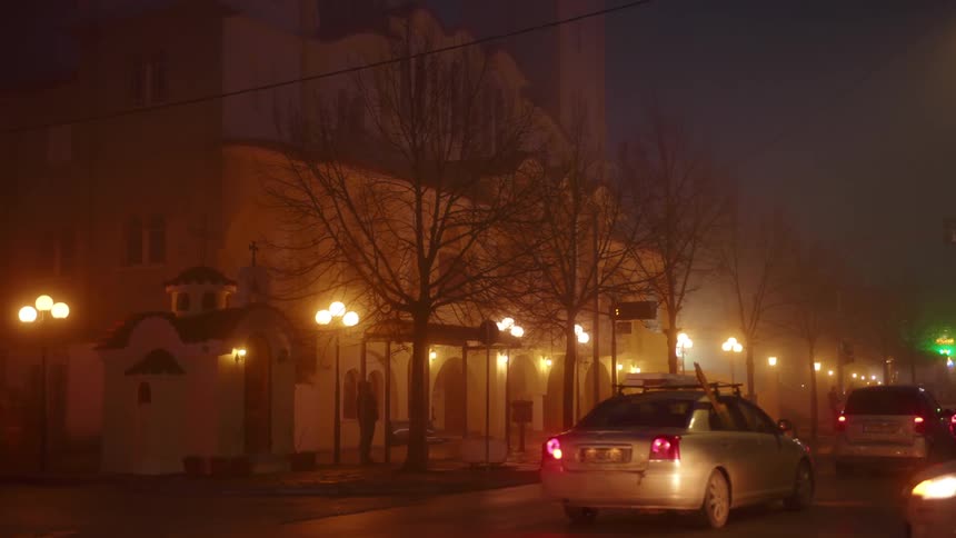 Cars are driving on a street at night