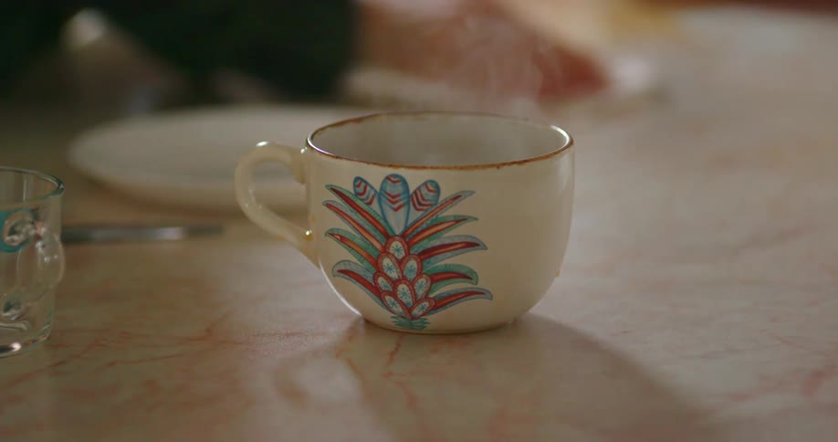 Person wipes marble counter near steaming tea cup