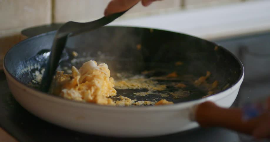 A woman cooking eggs at home