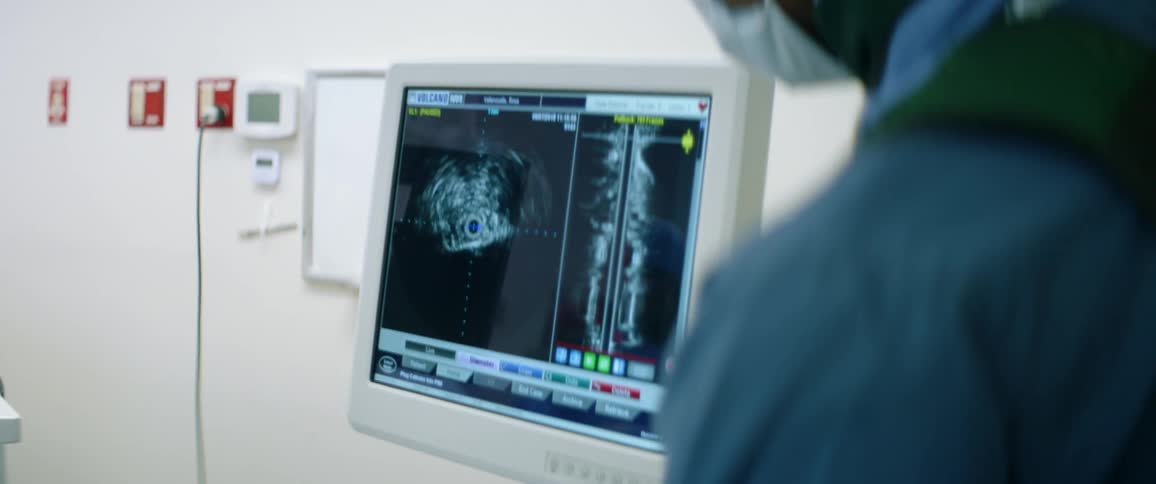 A medical professional points at the screen of an ultrasound machine