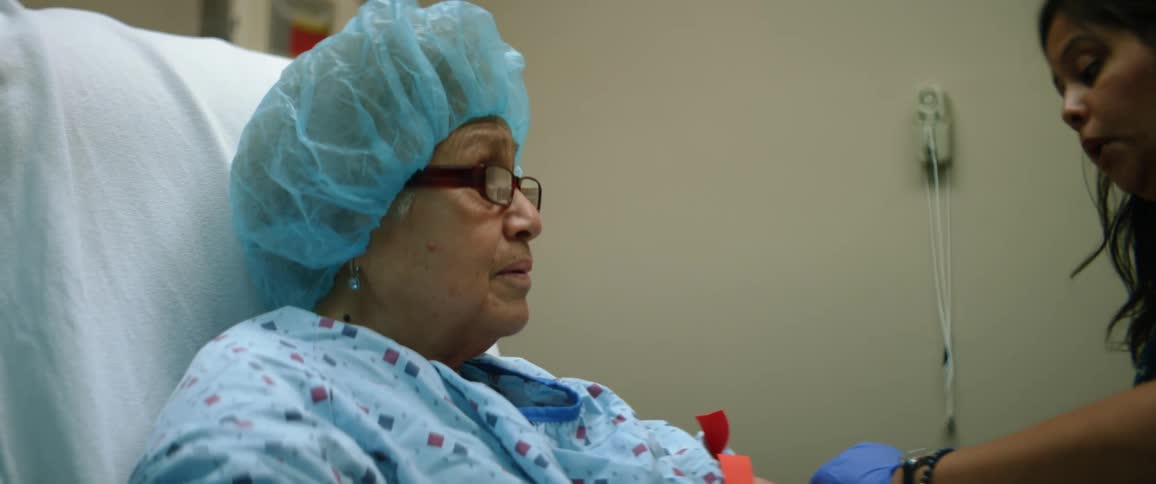 A nurse works on a female patient being prepped for surgery