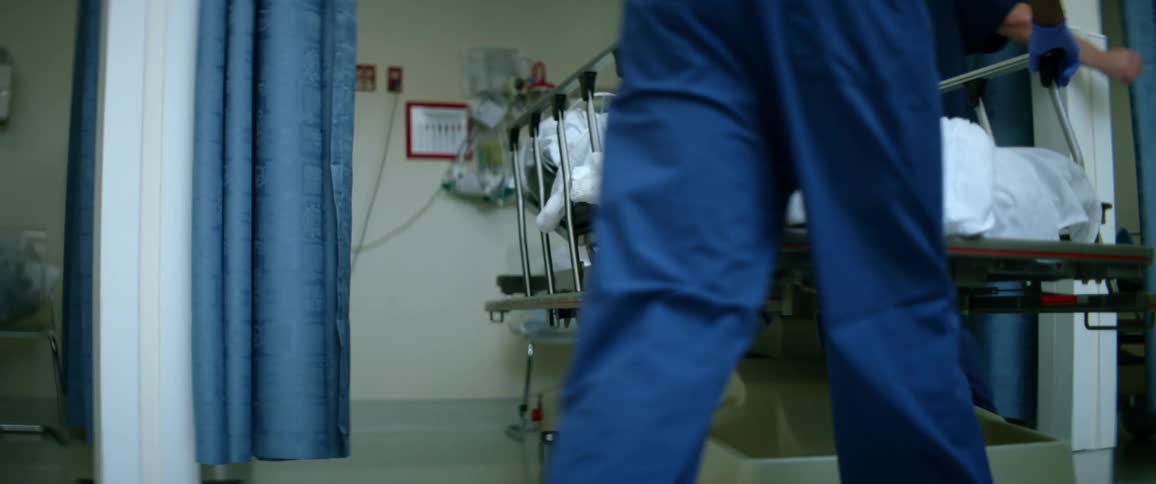 Nurses wheel patient on stretcher into room in hospital
