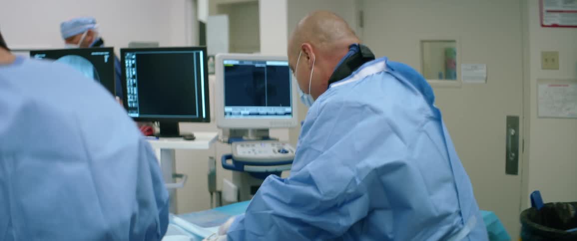 A group of medical professionals work quickly on a table beside equipment