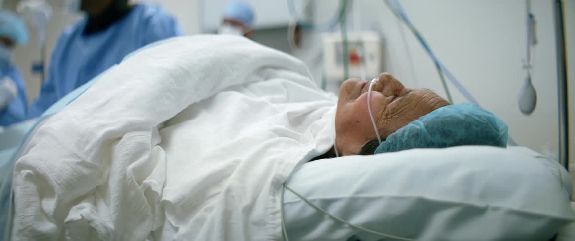 An elderly patient talks to her doctors while lying on an operating table