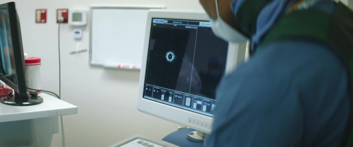 A person in a clinic looks at a computer screen as another man washes his hands