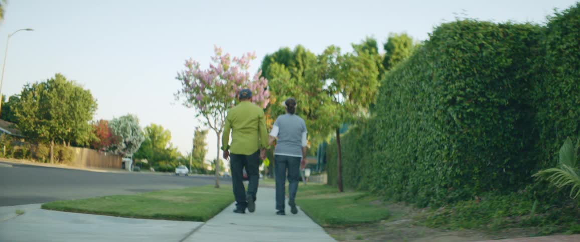Man and woman are walking in a neighborhood during the day