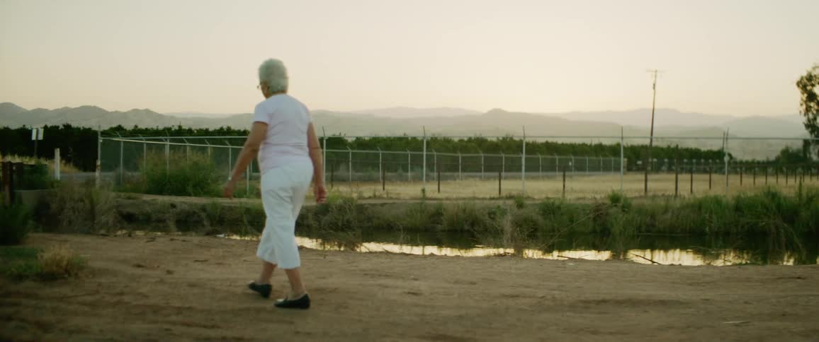 An elderly woman is walking in a rural area