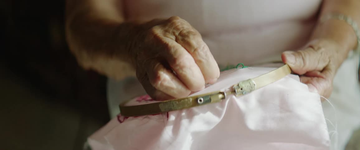 An elderly woman doing needlepoint at home