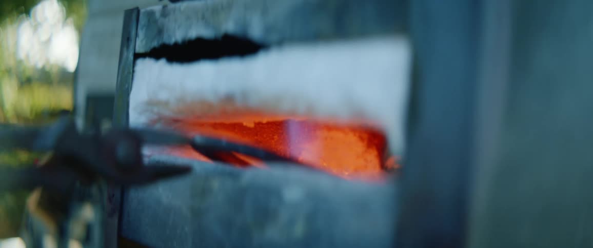 A horseshoe being heated up is pulled out of the flames