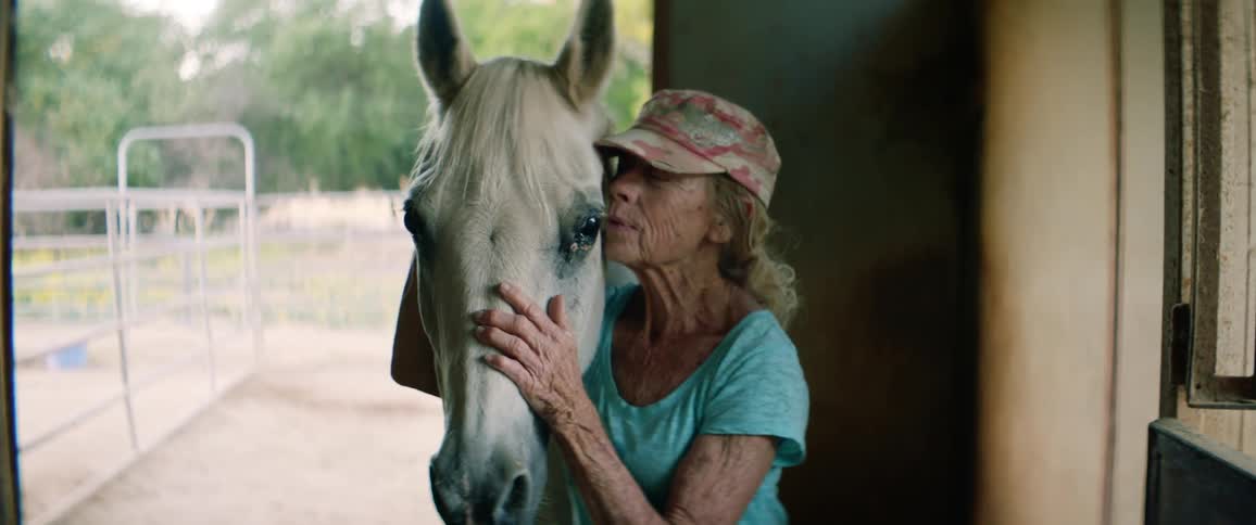A woman standing in a stable with her horse