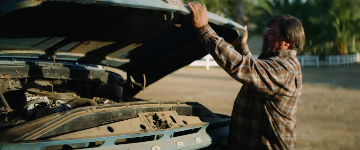 Man lifts hood of classic ford pickup truck