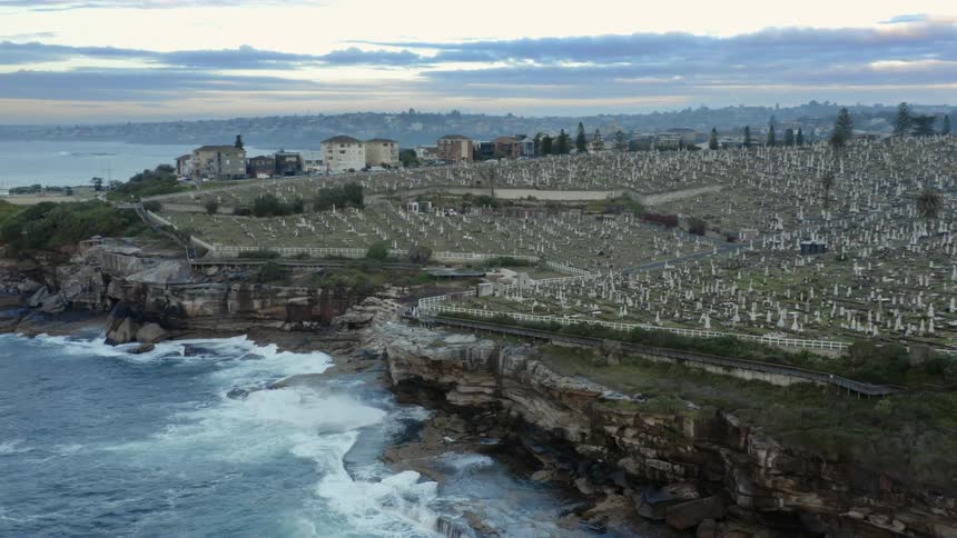 A large cemetery on a cliff above the ocean on a cloudy evening