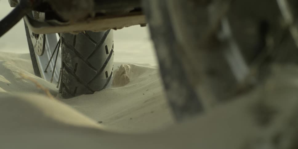 Tires on a vehicle dug into thick sand