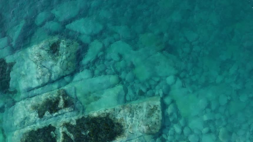 Large rocks and boulders under surface of clear blue ocean water