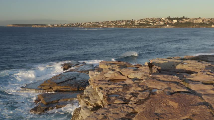 An aerial view of a person jumping rope on a cliffside next to a beach