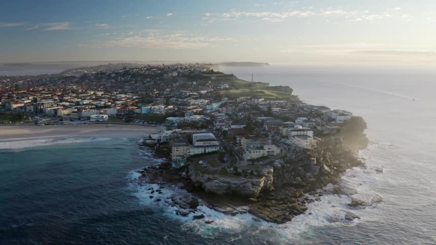 Large houses sit above a cliff on a peninsula next to the ocean