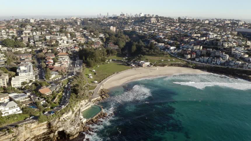 An aerial view of a houses in a neighborhood off the shore as waves roll in
