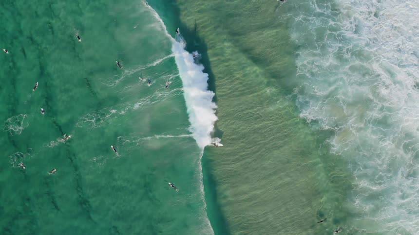 Surfers catching a wave on turquoise ocean water