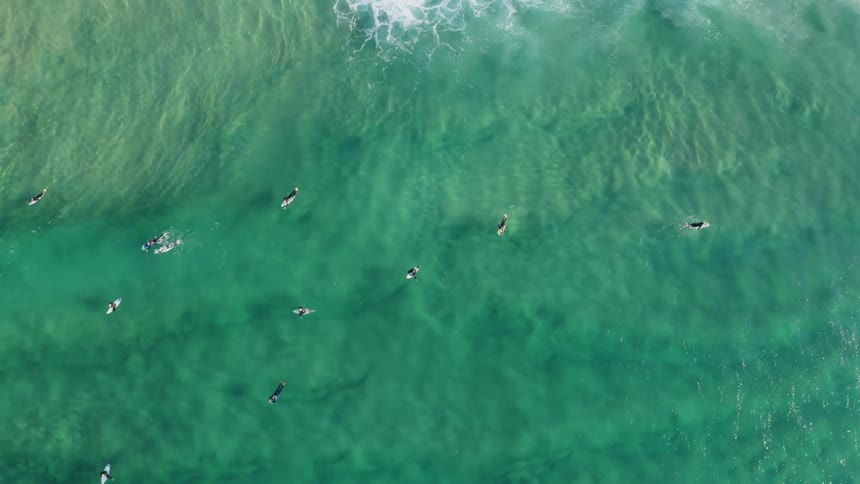 A birds eye view of surfers floating on turquoise ocean water