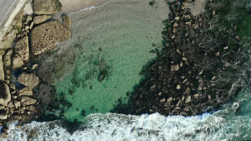 Person swimming near rocky coastline