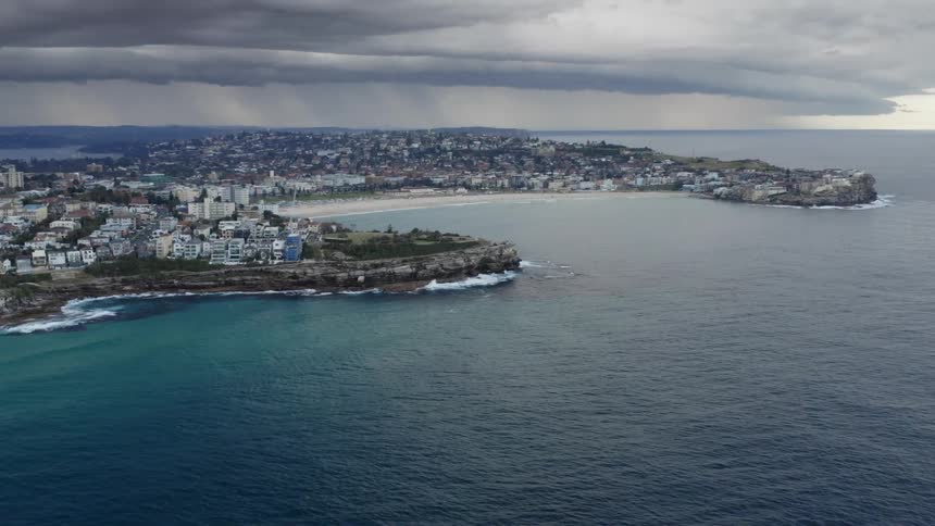 An aerial view of a coastal town with rain falling in the distance