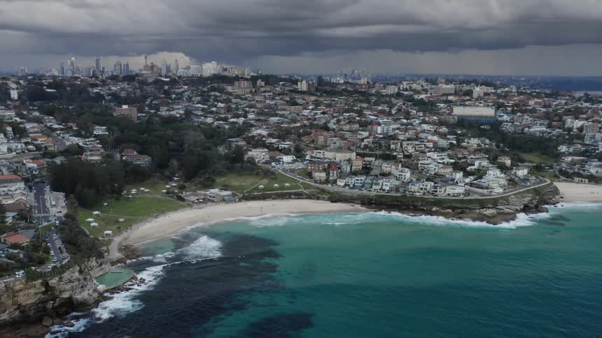An aerial view of a storm moving across a neighborhood and the shore
