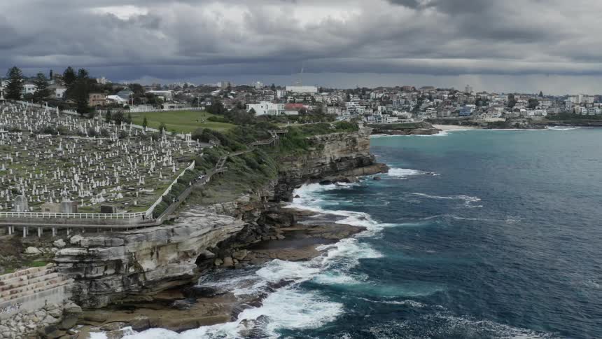 An aerial view of waves crashing in to the shore with a skyline in the distance