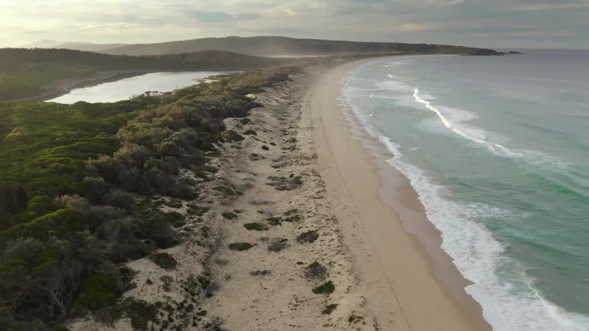 Aerial view of a beach at dusk is displayed