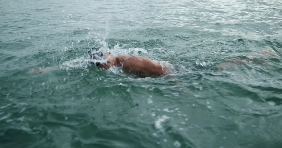 A man is swimming outdoors in the ocean