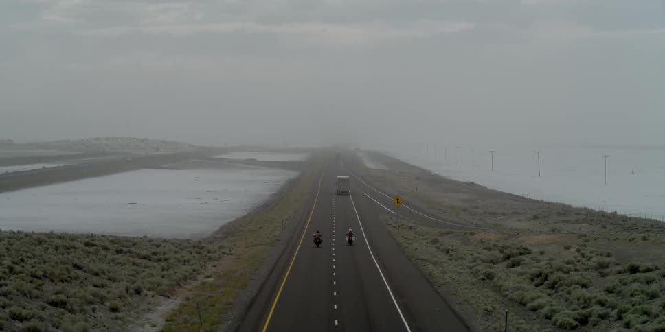 Vehicles drive down this small road on a foggy day