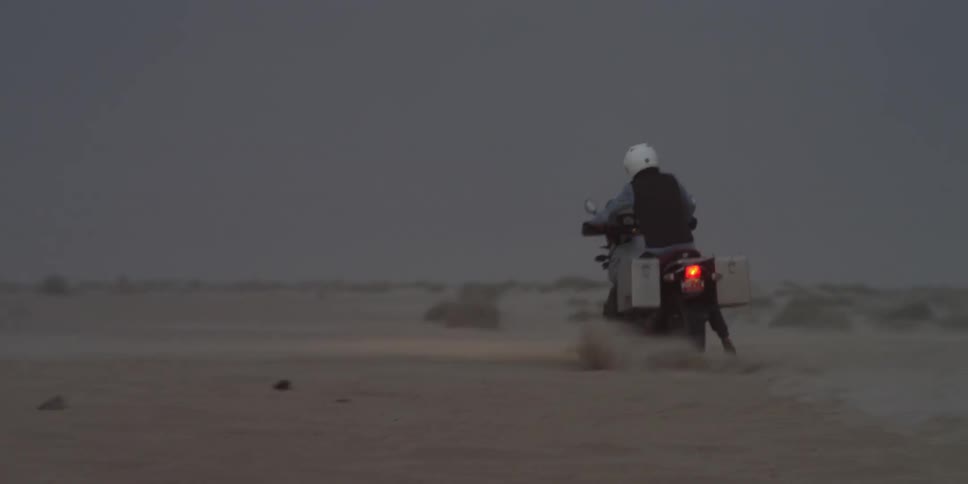 A motorcyclist rides through a dirt field