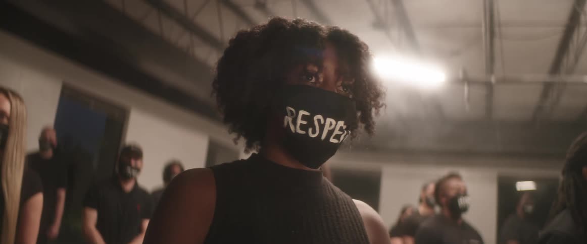 Group of people with face masks saying respect stand together in large room
