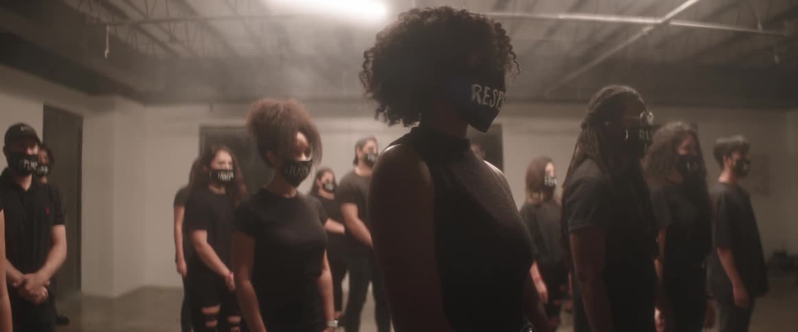 A group of people stand together in protest wearing face masks