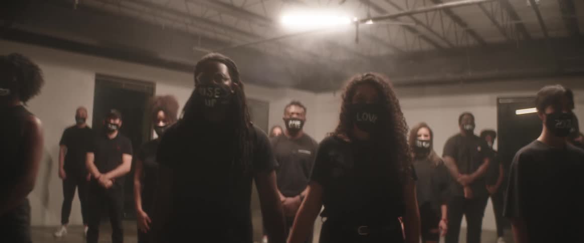 A group of people stand together in a basement with face masks promoting acceptance