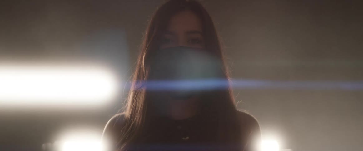 Woman in mask stands in front of strobing lights