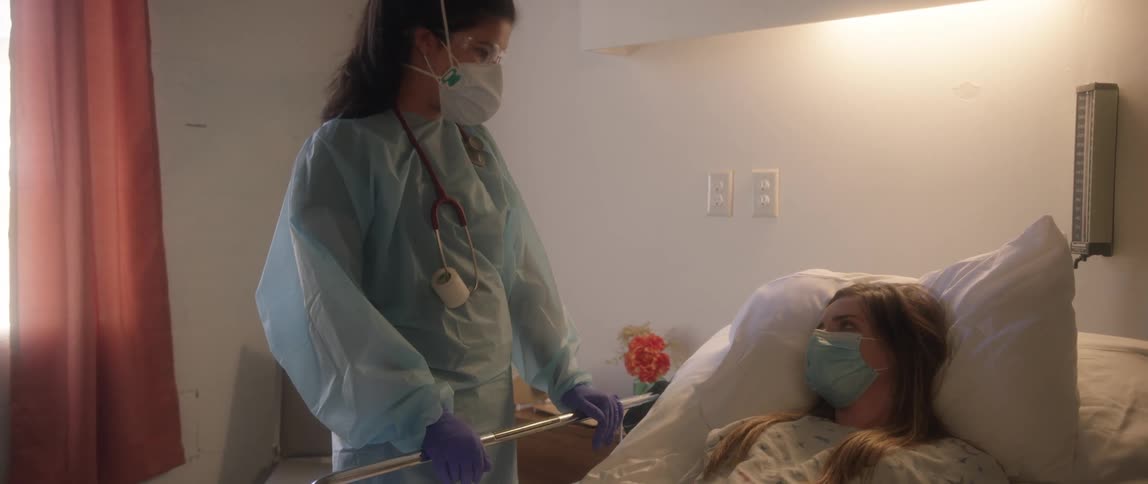 A female nurse walks into a room with a female patient and talks to her