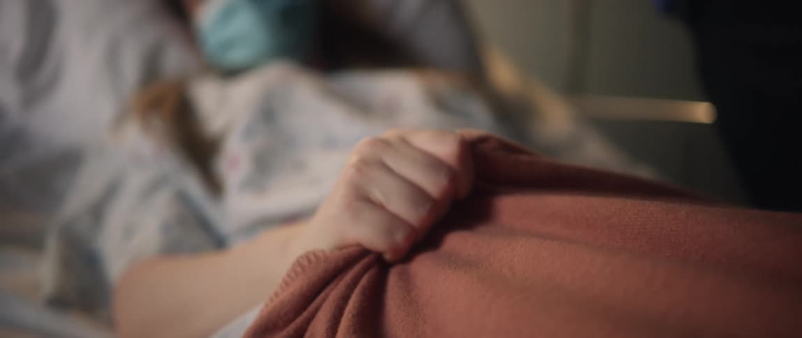 Patient laying on a hospital bed nervously clutching her blanket