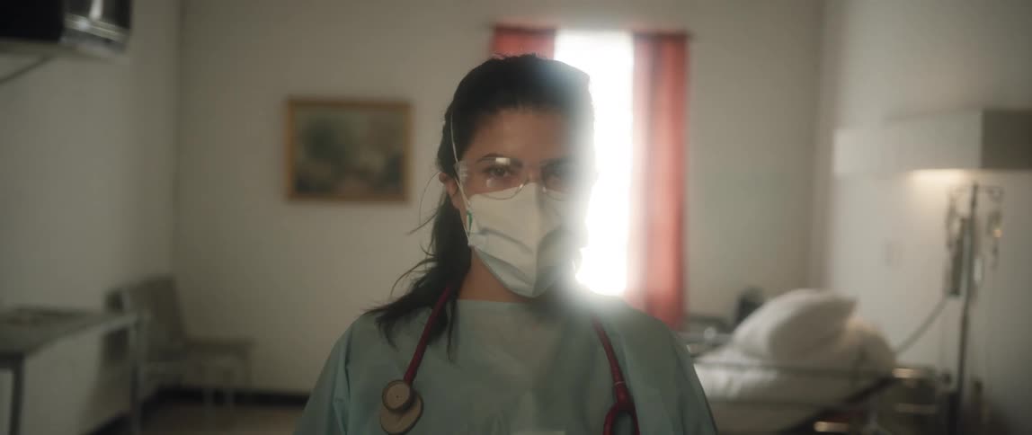Female doctor wearing a face mask stands in a patients room at the hospital