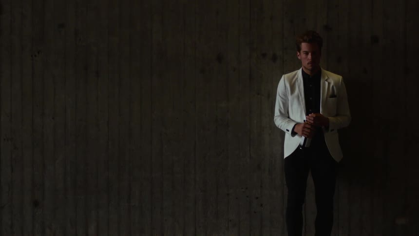 A man is standing indoors while holding a bottle