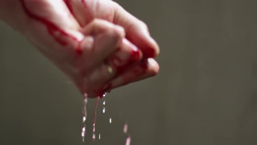 Water runs over a womans hand as blood drips from it