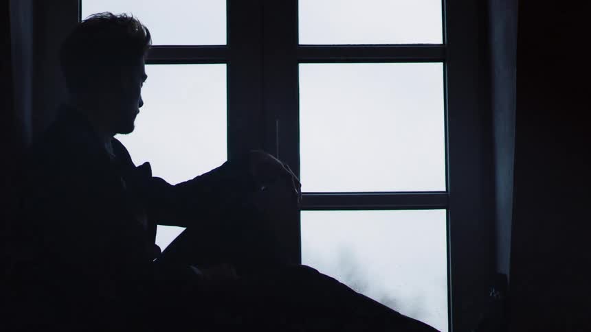 A man is sitting next to a window