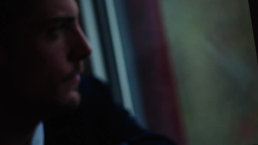 A man is sitting in a car and looking out a window